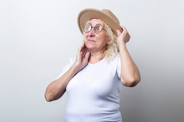 Old woman in a hat with glasses on a light background