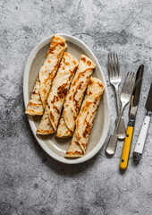 Crepes stuffed with tuna, avocado and egg on a grey background, top view
