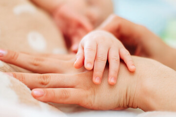 The little hand of the baby lies on the hand of the parent.