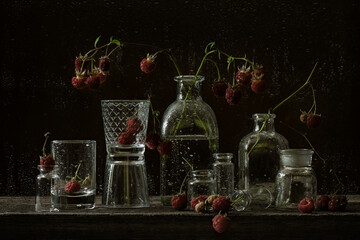 Still life in dark moody style with raspberries berries and glass