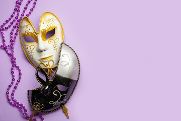 Two Venetian carnival masks are white and black on a lilac background. Mardi Gras concept. Top...