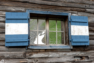 Reflection of mountains in the window of an old wooden house. Austria