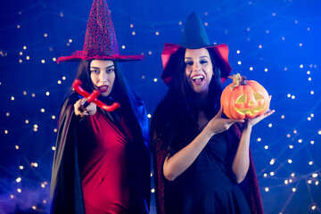 Studio shot of Asian Caucasian happy sexy female models in black red witch dress costume tall hat...
