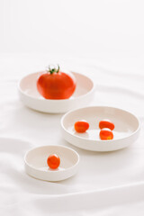 Fresh red tomatoes in white plate on white table
