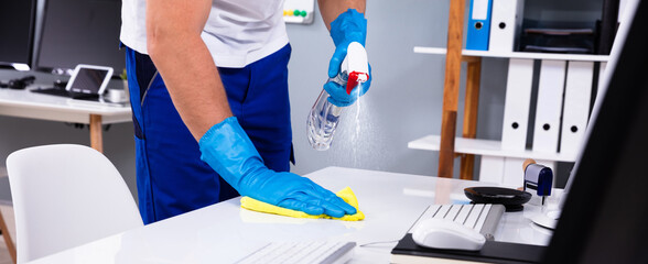Janitor cleaning white desk in office - obrazy, fototapety, plakaty