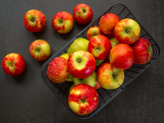 Apples, red, in a wire basket. Black background.