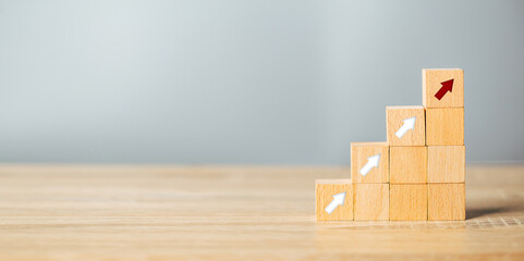 Arranging wood block stacking as step stair with arrow up.Ladder career path for business growth success process concept.