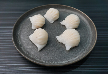 steamed har gao prawn wrapped in crystal skin dumpling on dark grey wood background dim sum menu