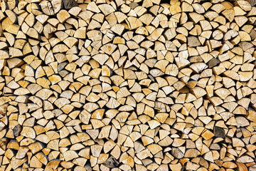 Stacked chopped wood close-up texture. Firewood storage background. Stocks of wooden logs. Chopping wood for a fireplace. Woodpile with firewood with visible wooden texture.