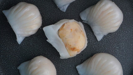 steamed har gao prawn wrapped in crystal skin dumpling in plate on dark grey wood table asian dim sum halal food restaurant cuisine banquet menu for cafe