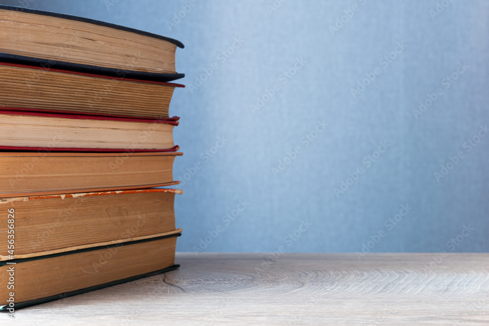 Poster stack of old books on wooden table and gray background with copy-space to right. background concept 