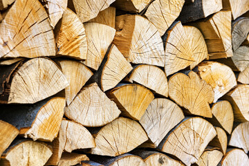 Fototapeta premium Stacked chopped wood close-up texture. Firewood storage background. Stocks of wooden logs. Chopping wood for a fireplace. Woodpile with firewood with visible wooden texture.