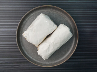 baked handmade paper wrapped chicken meat with herbal dark soy sauce on dark grey wood background dim sum menu
