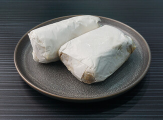 baked handmade paper wrapped chicken meat with herbal dark soy sauce in plate on dark grey wood table asian dim sum halal food restaurant cuisine banquet menu for cafe