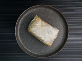 baked handmade paper wrapped chicken meat with herbal dark soy sauce on dark grey wood background dim sum menu