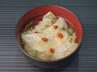 handmade deep fried and boiled pork meat dumpling wanton soup on dark grey wood background dim sum menu     