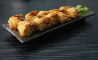 handmade deep fried and boiled pork meat dumpling wanton soup in plate on dark grey wood table asian dim sum halal food restaurant cuisine banquet menu for cafe
