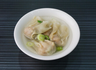 handmade deep fried and boiled pork meat dumpling wanton soup in plate on dark grey wood table asian dim sum halal food restaurant cuisine banquet menu for cafe