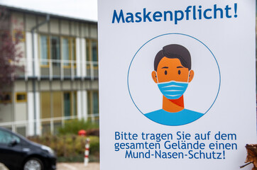 signpost wear a mask in german language