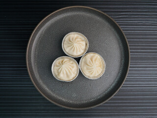 handmade steamed Shanghai Xiao long bao pork meat dumpling soup on dark grey wood background dim...