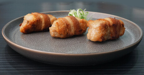 deep fried pork meatball wrapped with bacon roll on dark grey wood background dim sum menu