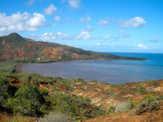 Obraz premium Green-orange-red-brown landscape with lake and mountains and blue sky.
