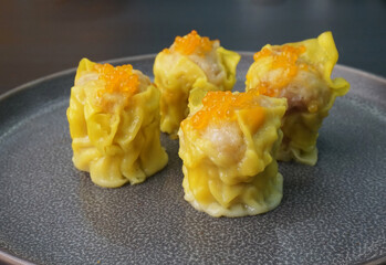 classic steamed fresh yellow stew mai dumpling wrapped with pork and fish roe caviar on dark grey wood background dim sum menu