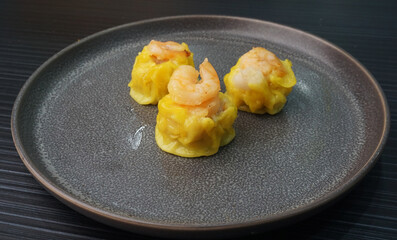 steamed fresh yellow stew mai dumpling wrapped with pork and prawn on dark grey wood background dim sum menu