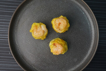 steamed fresh yellow stew mai dumpling wrapped with pork and prawn on dark grey wood background dim sum menu