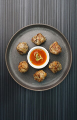 deep fried pork meatball with scallop and mushroom and chilli dip on dark grey wood background dim sum menu