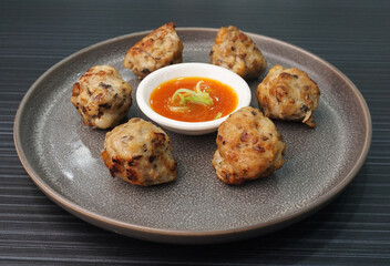deep fried pork meatball with scallop and mushroom and chilli dip on dark grey wood background dim sum menu