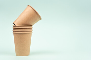 Set of disposable paper cups stacked in a row for drinks on a colorful background with copy space