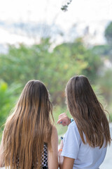 Couple of two young teenage girls with long blonde hair with their backs turned. White t-shirt and plaid shirt. Copy Space.