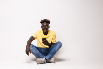 African man with a smart phone sitting on the floor