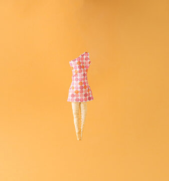 Parsley root like a woman's legs in dress on yellow background. Minimal arrangement.