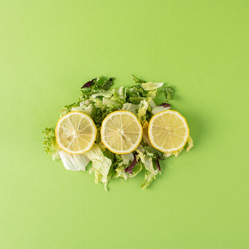Lemon slices on mixed salad against green background. Minimal summer concept.