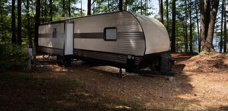 Camping Trailer In A Shady Spot Near The Water