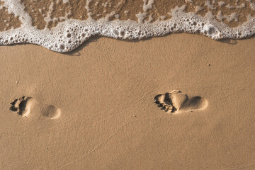 Footsteps on the beach by the sea in summer