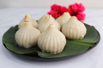 Obraz na płótnie Canvas Steamed or ukdiche Modak. It's a traditional sweet dish made out of coconut, jaggery and dry fruits stuffed inside rice dough. Offered to Lord Ganesha during Ganpati festival in India. with copy space
