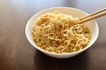 Instant noodles with chopsticks in a white bowl.