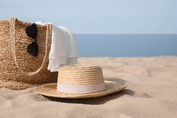 Beach bag, towel, sunglasses and hat on sandy seashore, space for text