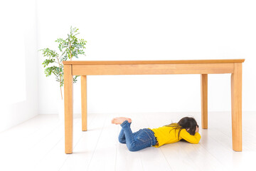 机の下に避難する子ども