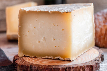 Close-up of a cured cheese cut into quarters, on a rustic wooden background.