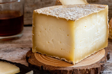 Close-up of a cured cheese cut into quarters, on a rustic wooden background.