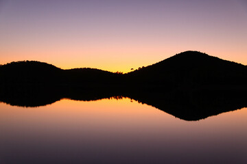 Horizonte en un atardecer cerca de un lago con el agua reflejada