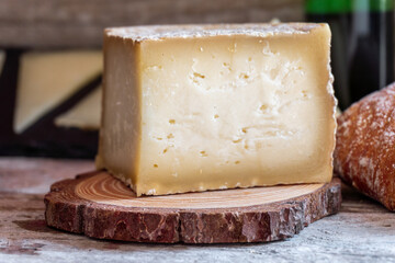 Close-up of a cured cheese cut into quarters, on a rustic wooden background.