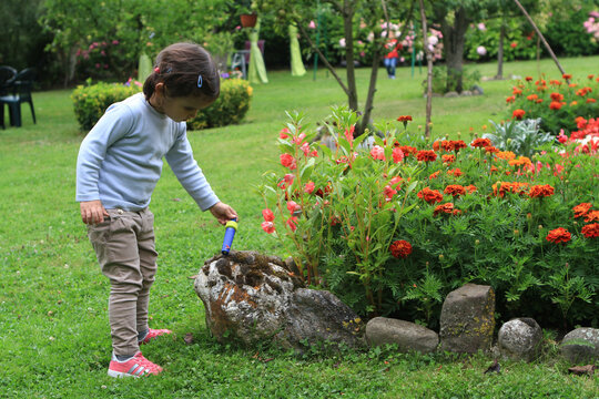 Niña jugando en jardín con flores