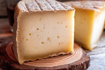 Close-up of a cured cheese cut into quarters, on a rustic wooden background.