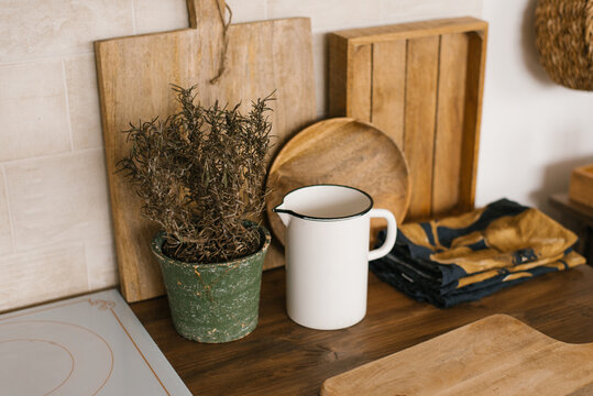 White metal milk jug, potted flowers, cutting board and kitchen decor