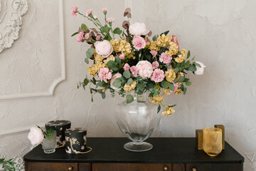 A luxurious bouquet of flowers in a glass vase stands on the dresser. home interior decor